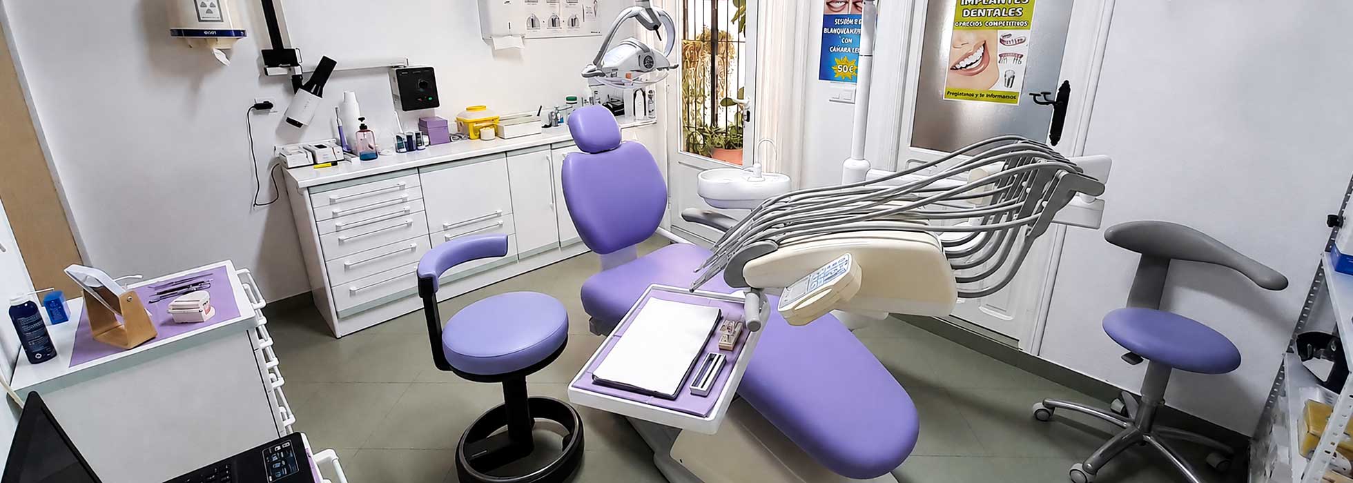 Clínica dental moderna con sillón odontológico en tonos morados y equipamiento profesional.