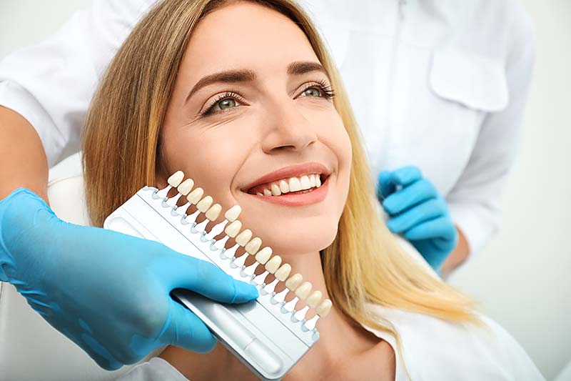 Dentista que combina el color de los dientes de un paciente con una paleta.