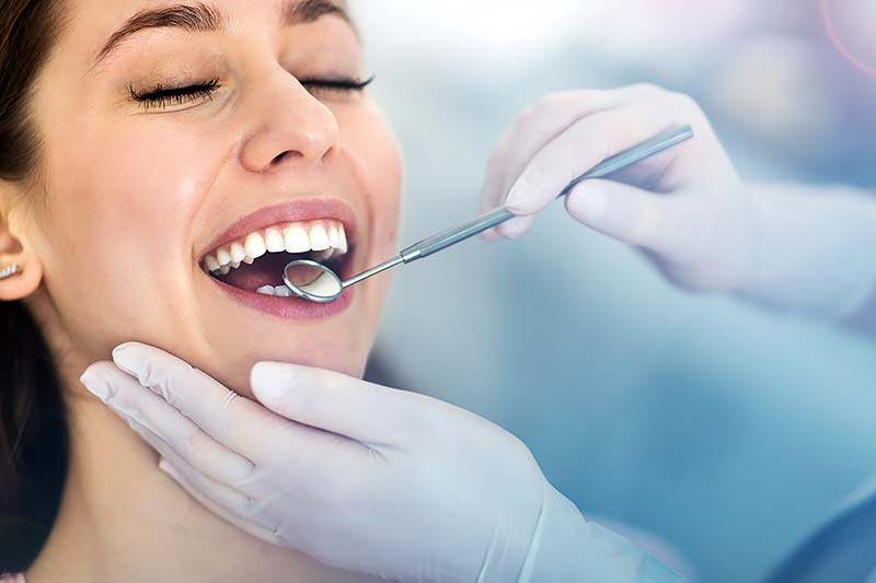 Dentista realizando una revisión dental a una paciente sonriente.