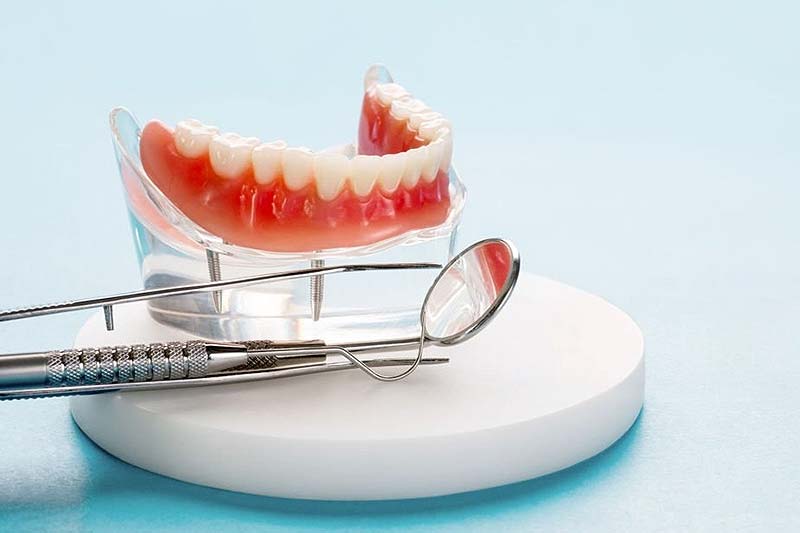 Prótesis dental completa y herramientas de exploración clínica.